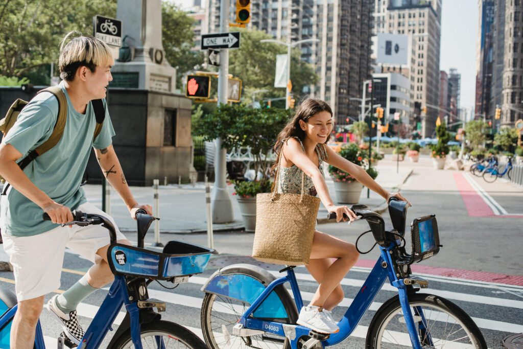 Happy couple cycling together on city streets, enjoying a sunny day and urban vibe.